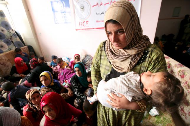 A displaced woman carries her child in a building that is used as a temporary shelter in Makhmour area, southeast of Mosul. REUTERS/Azad Lashkari