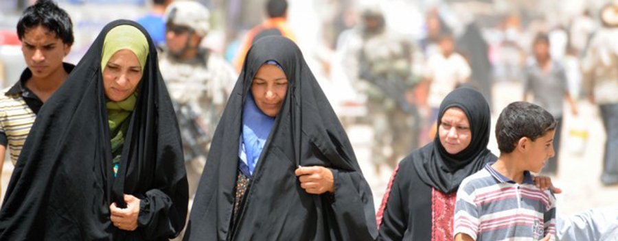 Iraqi women walk down a busy market street in eastern Baghdad, Iraq, June 21