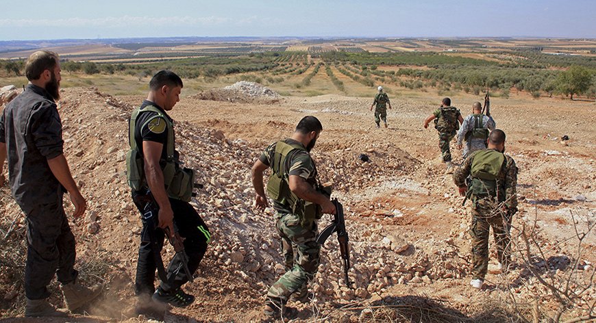 Forces loyal to Syria's President Bashar al-Assad carry their weapons as they walk in the village and hill of Al-Samsam in Hama countryside, after saying they have regained control of the area September 13, 2014. REUTERS/George Ourfalian (SYRIA - Tags: POLITICS CIVIL UNREST CONFLICT MILITARY) - RTR463AI