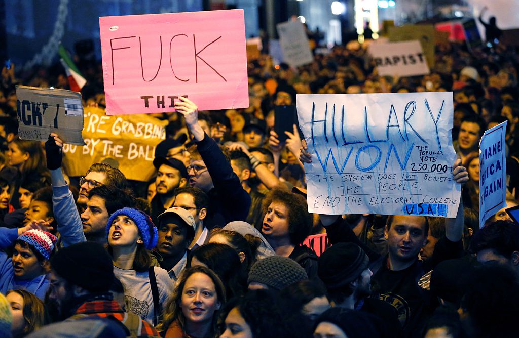 Although a tad bit more eloquent than the sign on the left, the sign on the right illustrates the total misunderstanding of the U.S. electoral process.