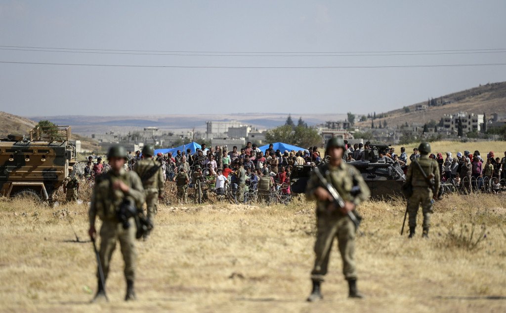 Turkish soldiers guard crowds near the Syrian border on June 26. The Turkish government's proposed 'safe zones' for Syrian refugees may require a significant military presence, experts say. BULENT KILIC/AFP/GETTY IMAGES