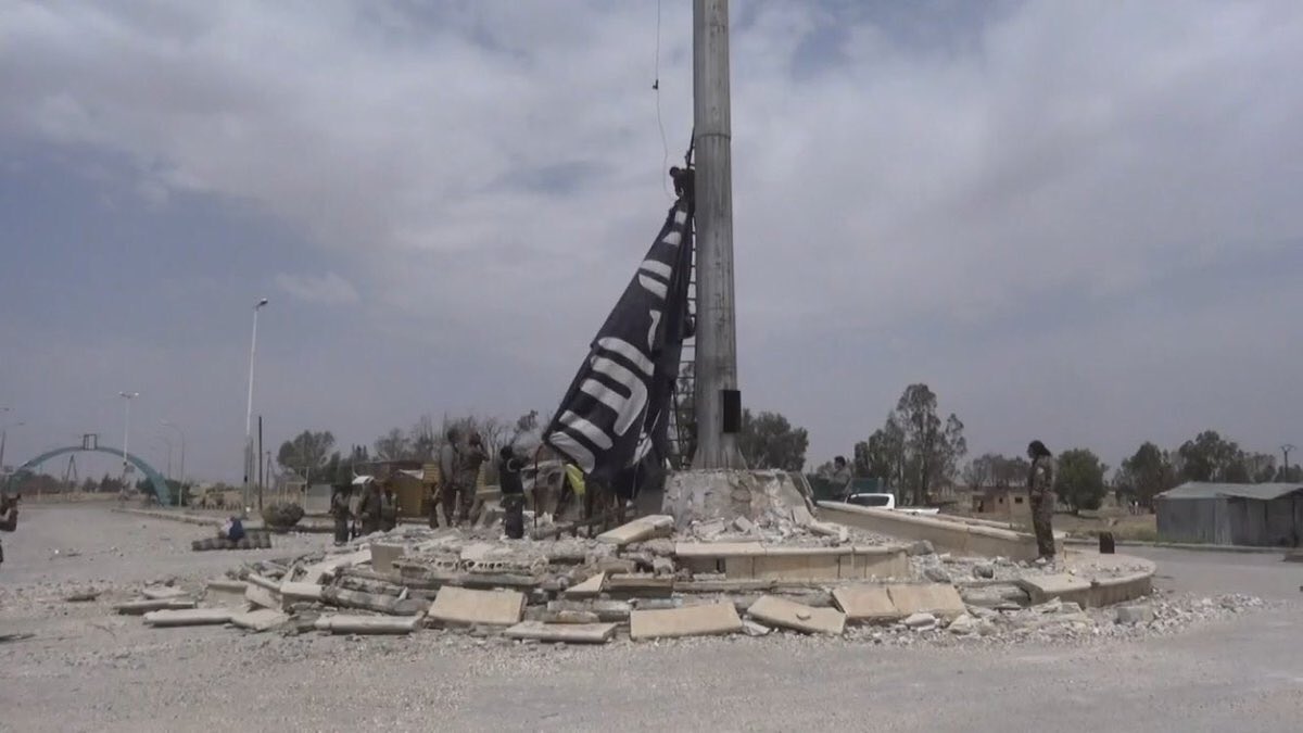 A SDF member is removing an ISIS flag from the center of Tabqa
